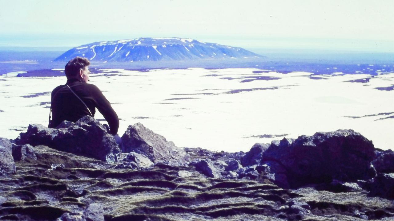 a man sitting on rocks and looking out